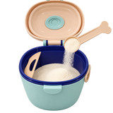 A plastic baby food storage container with a light blue-green body, dark blue inner rim, and peach-colored lid and scoop, shown open with white rice being poured into the container against a white background.
