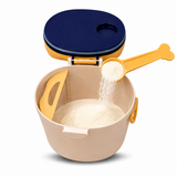 A beige plastic baby food storage bowl with a yellow and navy blue lid, shown with a yellow measuring scoop pouring white powder into the bowl on a white background.