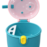 A children's plastic cup and lid set in teal and pink, shown open with a white spoon inside. The cup body is teal with a yellow latch, and the lid is pink with a clear plastic top and blue accents.